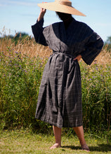 Load image into Gallery viewer, Woman wearing brown checked kimono and large straw hat with summer field background