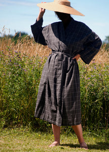 Woman wearing brown checked kimono and large straw hat with summer field background