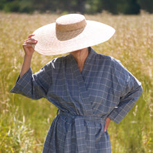 Load image into Gallery viewer, Woman wearing dove blue grey kimono with checks and large straw hat with a summer field background