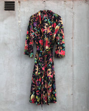 Load image into Gallery viewer, Colorful black floral-patterned dress hanging against a gray wall