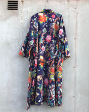 Load image into Gallery viewer, Back side of floral patterned dark blue kimono robe on a textured cement wall