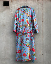 Load image into Gallery viewer, Colorful floral and bird patterned garment hanging on a concrete wall.