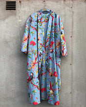 Load image into Gallery viewer, Colorful light blue floral and bird-patterned kimono robe hanging against a concrete wall.