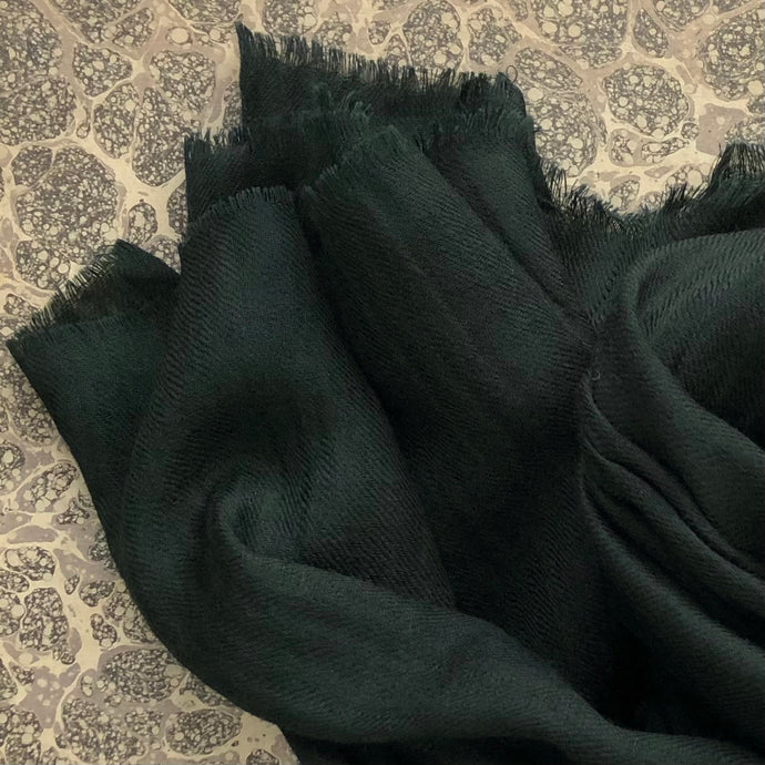 dark green wool scarf on grey marble paper background