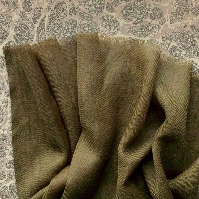 olive green wool scarf on marble paper background