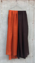 Load image into Gallery viewer, Two pairs of wool scarves, one orange and one brown, hanging on a concrete wall.