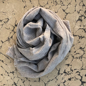 Soft stone beige wool scarf rolled on marbled beige paper