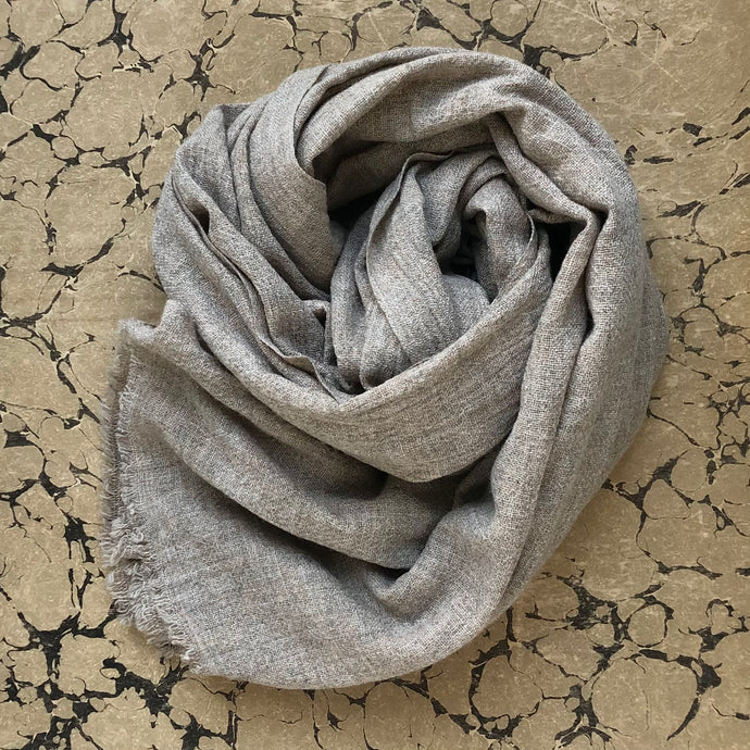 Soft stone beige wool scarf rolled on marbled background