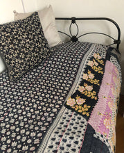 Load image into Gallery viewer, Quilt with floral patterns on a bed with a black metal frame.