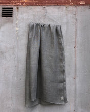 Load image into Gallery viewer, Grey linen scarf hanging on a hanger against a concrete wall.