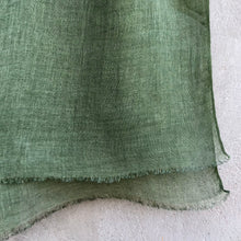 Load image into Gallery viewer, Close-up of a sage green linen scarf against a textured concrete wall.