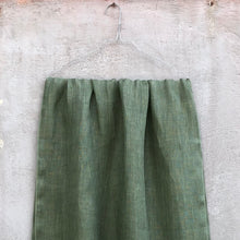 Load image into Gallery viewer, Sage green linen scarf on hanger against a textured concrete wall.